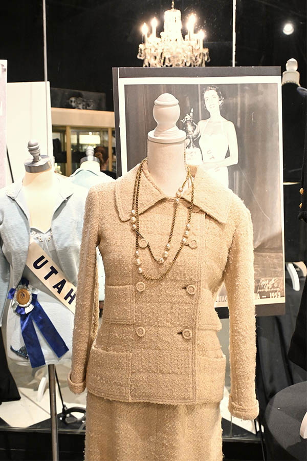 A-display-shows-two-mannequins,-one-in-a-beige-tweed-suit-with-a-pearl-necklace-and-another-in-a-light-blue-suit-with-a-“UTAH”-sash,-with-a-large-black-and-white-photo-behind-them