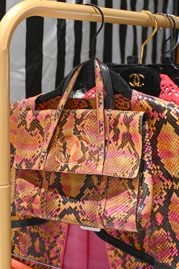Chanel-python-skin-bag-in-shades-of-pink-and-orange-is-hanging-on-a-clothing-rack-with-a-matching-garment-behind-it