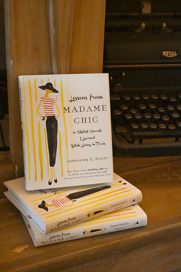 book-display-featuring-three-copies-of-the-book-Lessons-from-Madame-Chic-20-Stylish-Secrets-I-Learned-While-Living-in-Paris