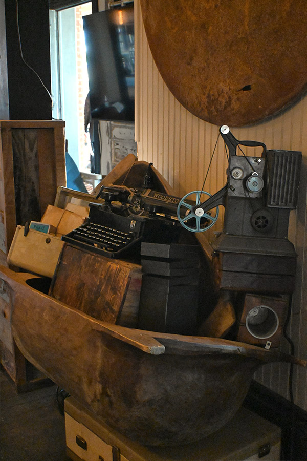 decorative-display-featuring-an-old-black-typewriter-with-the-word-WOODSTOCK-on-it-and-an-antique-film-projector-or-machine