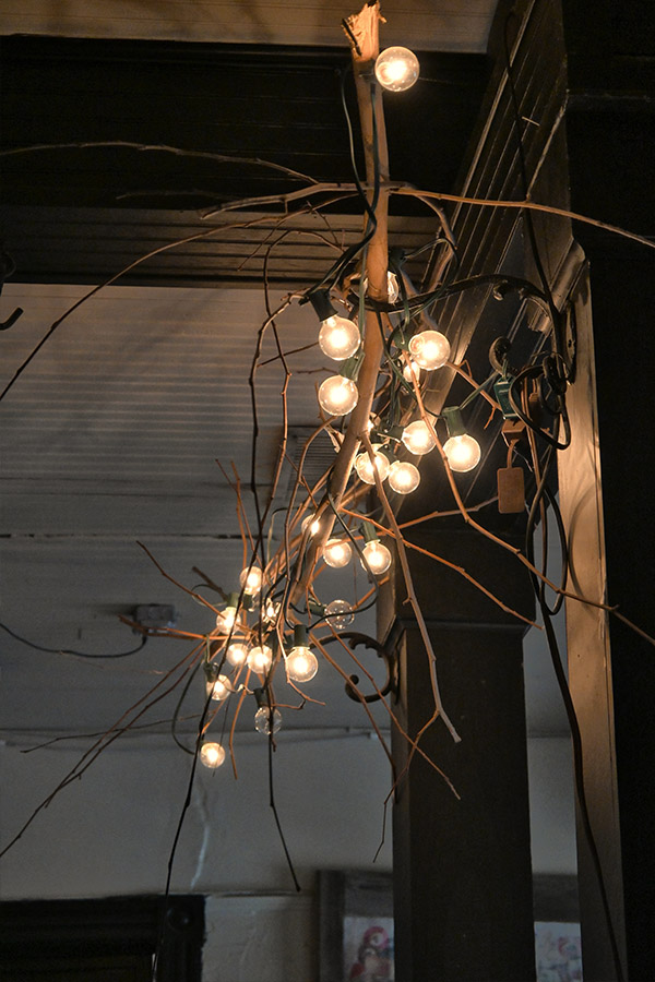 decorative-light-fixture-made-from-a-cluster-of-bare-wooden-branches-that-are-wrapped-with-strands-of-small-glowing-lightbulbs
