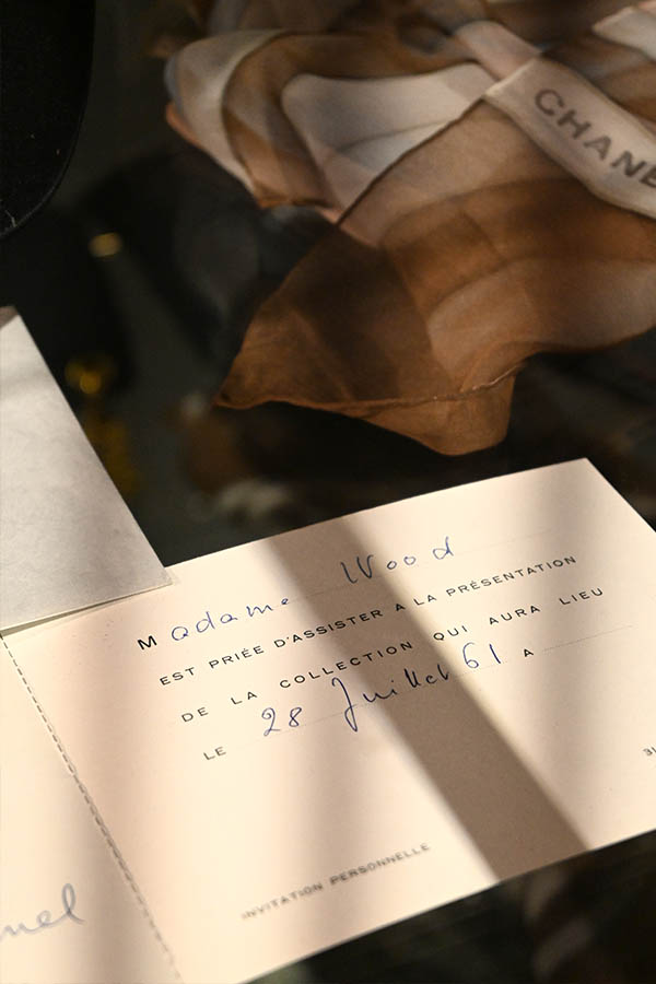 display-case-shows-a-folded-sheer-Chanel-scarf,-an-envelope-marked-“PAR-AVION,”-and-an-invitation-card-from-Mademoiselle-Chanel-for-the-1961-62-Winter-Collection