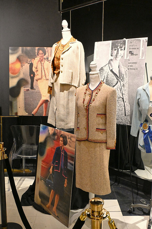 display-features-two-mannequins-wearing-Chanel-style-tweed-suits-and-necklaces-alongside-photographic-and-illustrated-posters-of-women-in-similar-fashion.