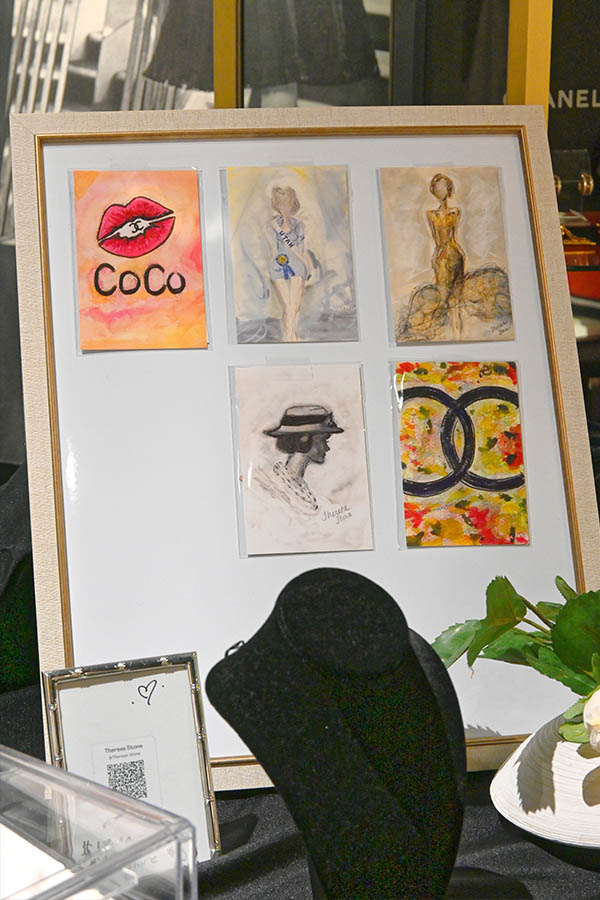 framed-display-shows-six-small-artworks-including-a-painting-of-red-lips-with-“Coco”-written-below,-fashion-illustrations-of-women,-and-a-colorful-Chanel-logo-design