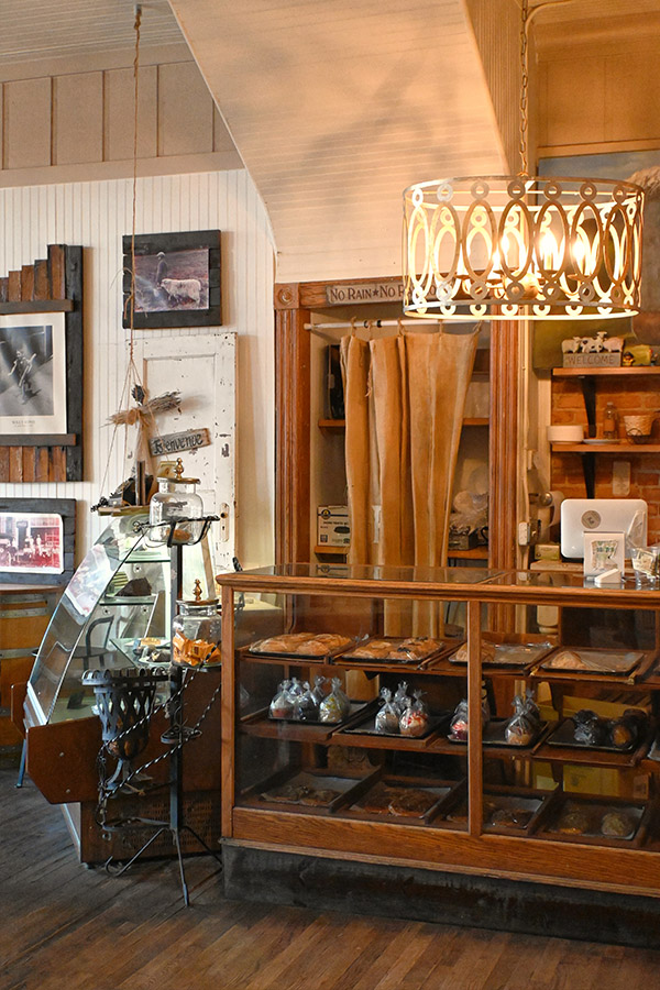 french-interior-of-a-cafe-or-bakery-with-a-large-wooden-and-glass-display-case-in-the-foreground-filled-with-various-pastries-and-baked-goods