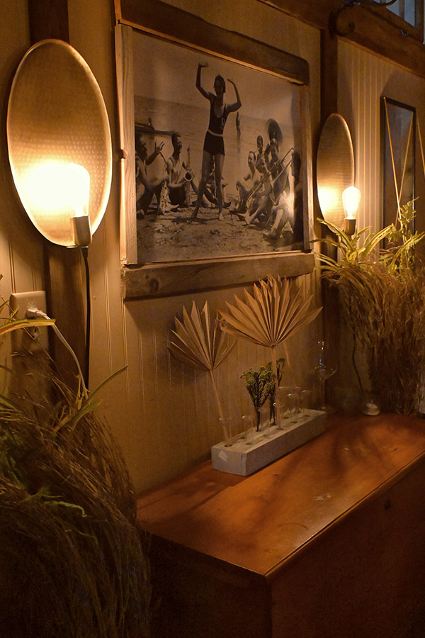 french-interior-space-lightbulb-on-each-side-and-the-dresser-is-decorated-with-dried-palm-fronds-in-a-gray-rectangular-vase