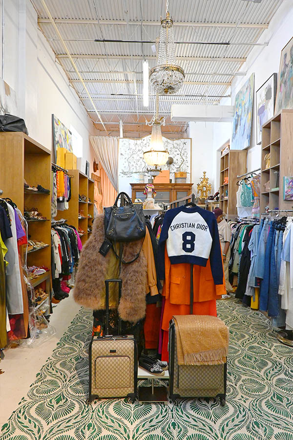intage-style-clothing-store-interior-is-shown-with-a-christian-dior-branded-jersey-on-a-mannequin-two-gucci-monogrammed-suitcases-and-a-large-fur-coat