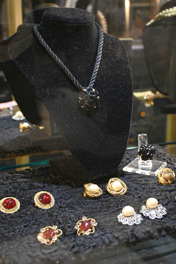 jewelry-display-is-shown-with-a-black-velvet-bust-holding-a-pendant-necklace-and-a-collection-of-earrings-and-rings-featuring-pearls-and-red-stones-on-a-black-textured-surface.