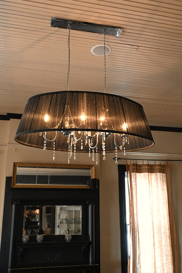 large-chandelier-with-a-black-pleated-shade-and-hanging-crystal-pendants-suspended-from-a-wooden-plank-ceiling