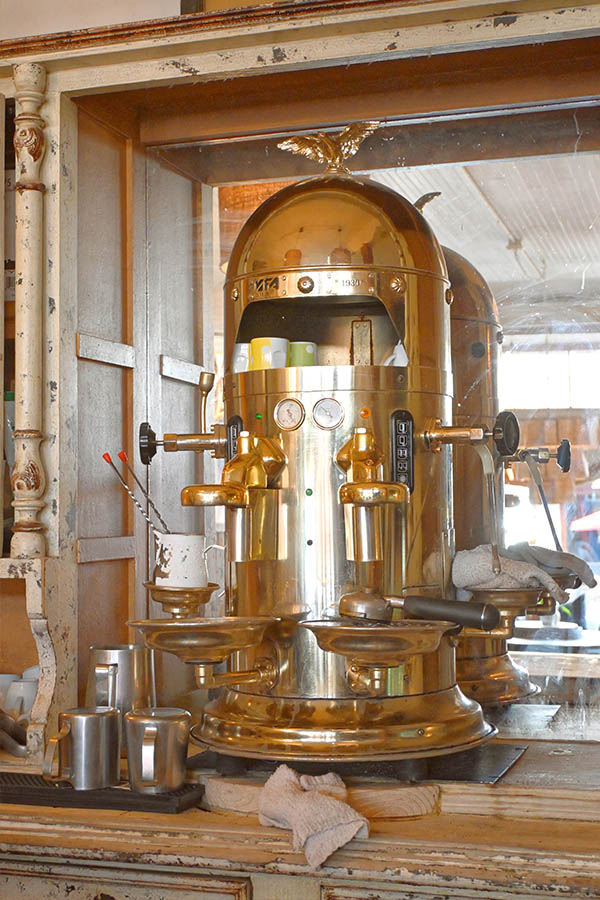 large-vintage-style-brass-espresso-machine-with-an-eagle-ornament-on-top-gauges-and-multiple-levers-that-is-sitting-on-a-counter