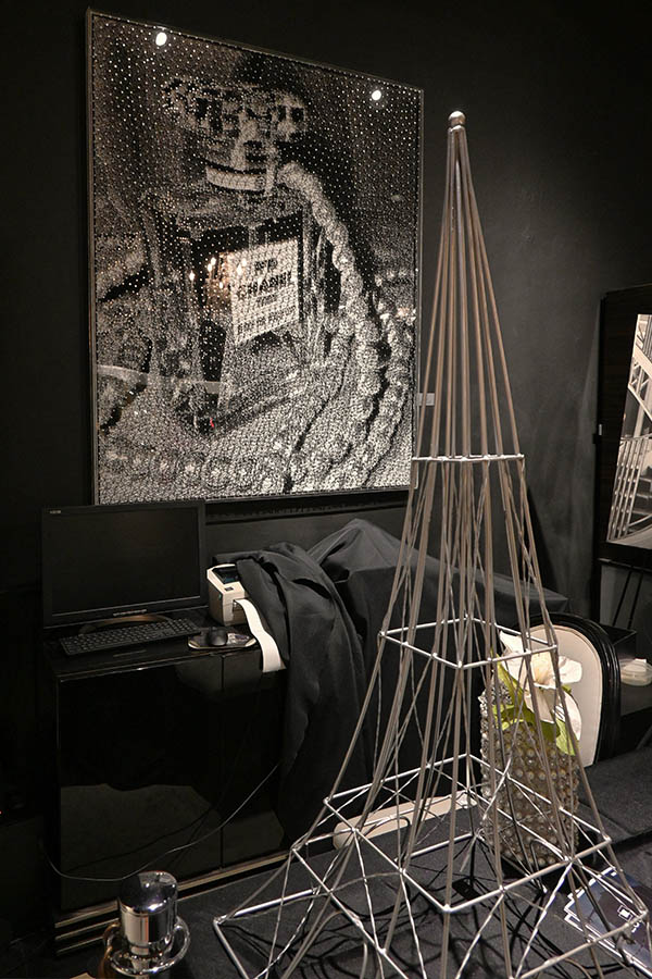room-display-features-a-large-bedazzled-Chanel-No.-5-perfume-bottle-artwork-on-a-wall-above-a-black-cabinet-and-a-large-metal-Eiffel-Tower-sculpture-in-the-foreground
