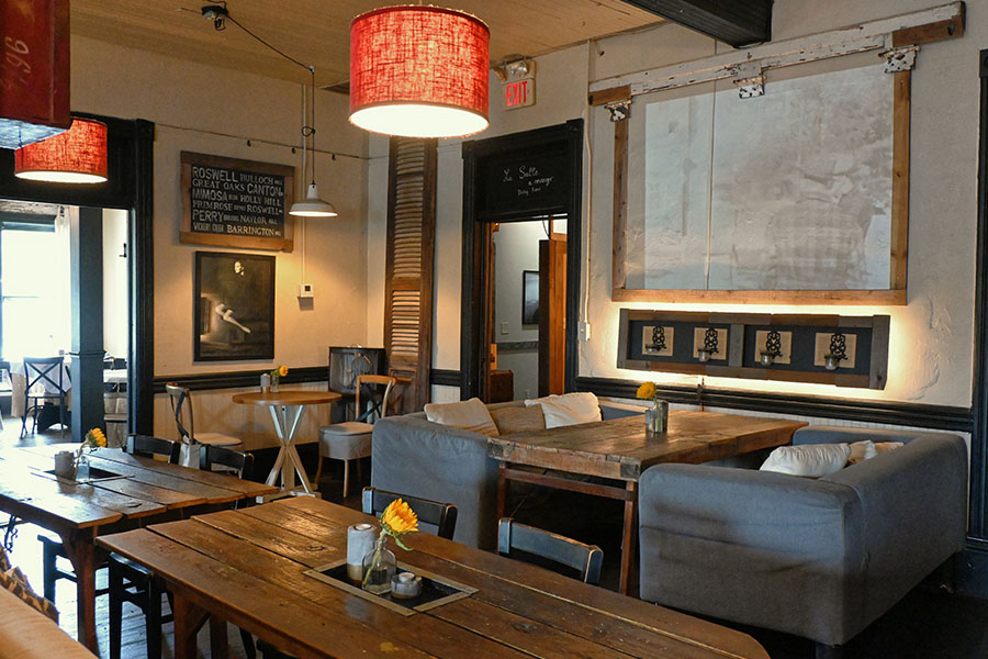 rustic-and-vintage-design-style-of-a-restaurant-or-cafe-interior-with-a-long-wooden-communal-table-in-the-foreground-and-a-couch-style-booth-in-the-middle-of-the-room