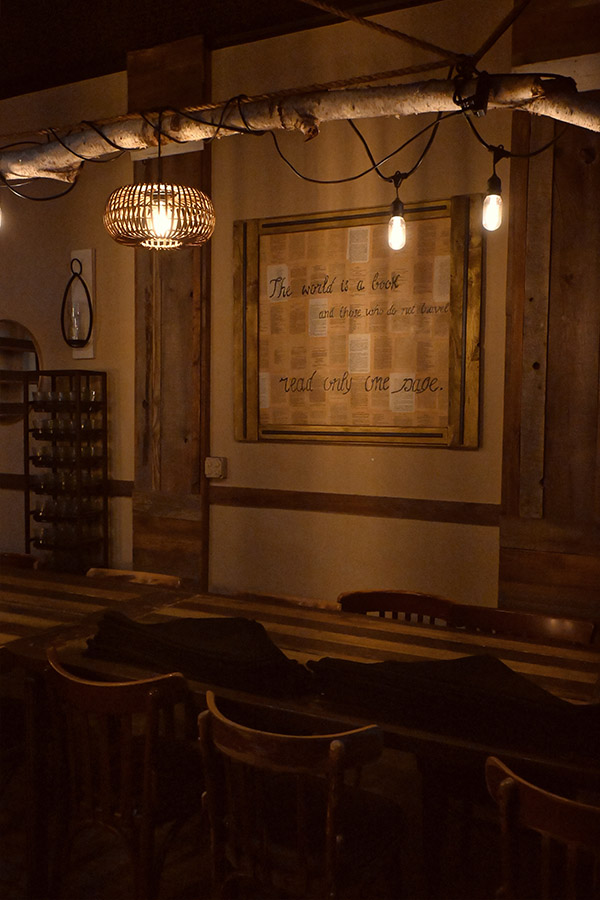 rustic-and-vintage-design-style-of-an-interior-dining-area-with-a-wooden-table-and-chairs-and-a-framed-quote-on-the-wall-The-world-is-a-book-and-there-wins-&-met-bevie-read-only-one-page