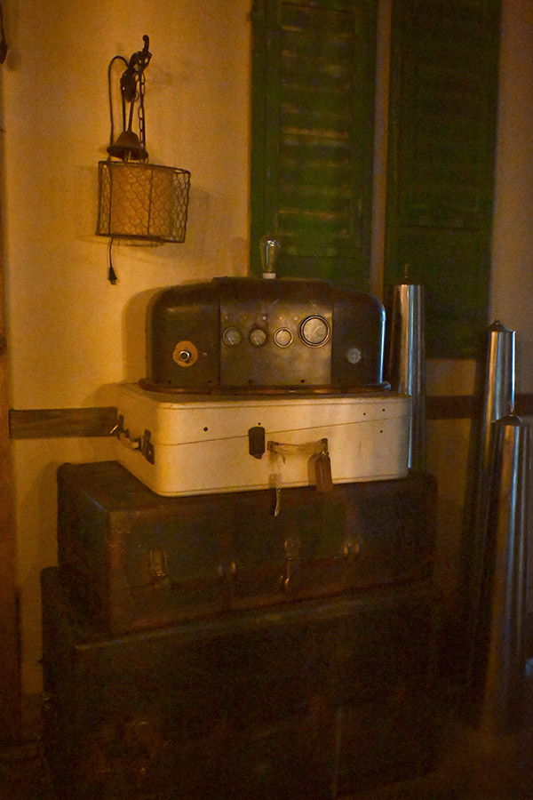 rustic-and-vintage-design-style-with-a-stack-of-old-suitcases-including-a-light-colored-one-in-the-middle-and-on-top-of-the-stack-is-a-dark-and-industrial-looking-machine