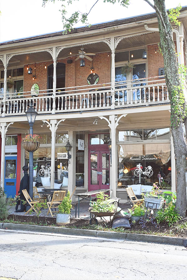 two-story-brick-building-with-a-wrap-around-porch-balcony-on-the-second-floor-and-a-ground-level-storefront-with-outdoor-seating-and-the-name-Roswell-Provisions- french-restaurant