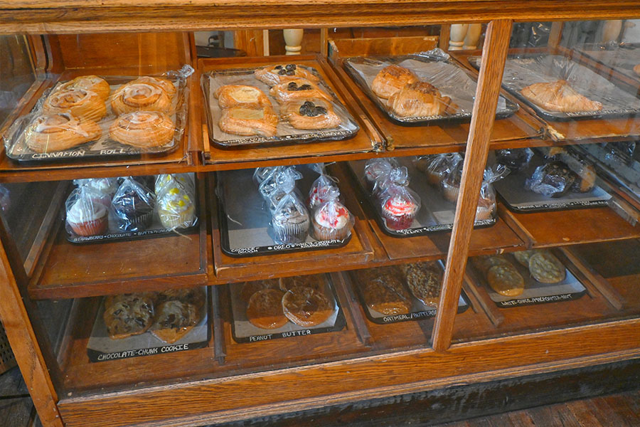 vintage-design-style-wooden-and-glass-display-case-filled-with-various-baked-goods-including-cinnamon-rolls-pastries