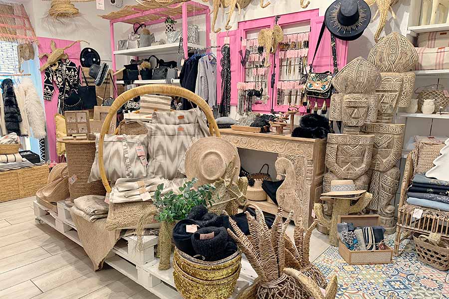 Bohemian-boutique-filled-with-an-eclectic-mix-of-neutral-toned-pillows-straw-woven-animal-sculptures-carved-wooden-totems-and-black-accessories