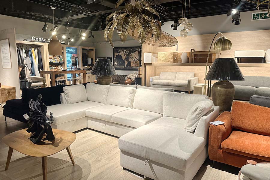 Modern-retail-furniture-showroom-featuring-a-white-L-shaped-sectional-sofa-positioned-on-light-wood-flooring-surrounded-by-various-seating