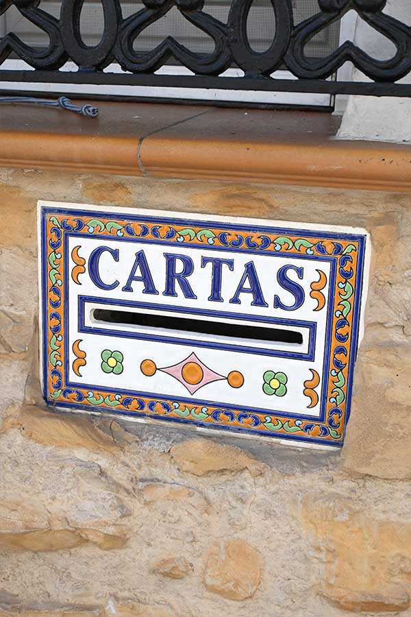 decorative-ceramic-mail-slot-tile-labeled-CARTAS-is-embedded-in-a-rough-stone-wall