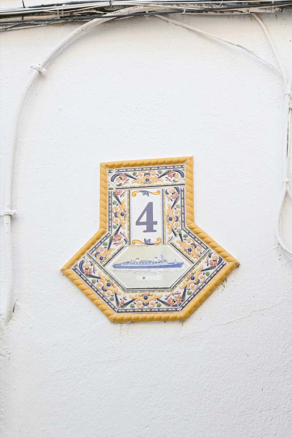 decorative-ceramic-wall-plaque-featuring-the-number-four-is-mounted-on-a-white-textured-exterior-wall