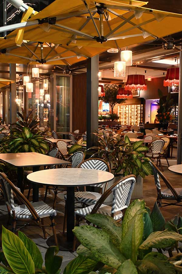 outdoor-dining-patio-is-furnished-with-round-marble-topped-tables-and-black-and-white-chevron-patterned-chairs