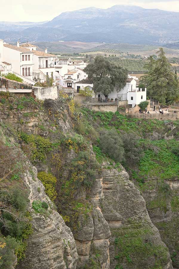 panoramic-view-of-white-washed-buildings-perched-precariously-on-the-edge-of-a-massive-sheer-rock-cliff