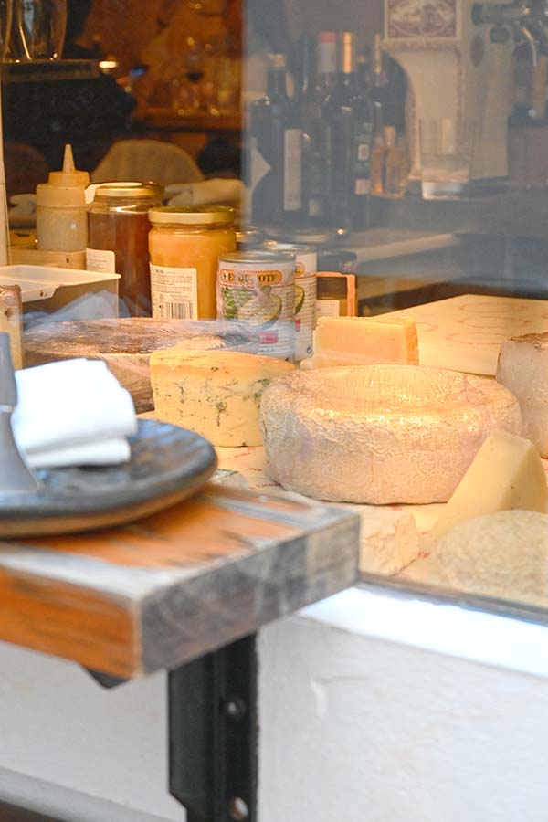 storefront-display-window-showcases-various-rounds-of-cheese-wrapped-in-plastic-alongside-jars-of-honey
