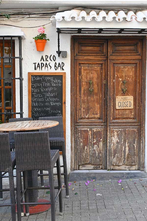 weathered-wooden-double-door-at-Arco-Tapas-Bar-features-two-vintage-brass-knockers