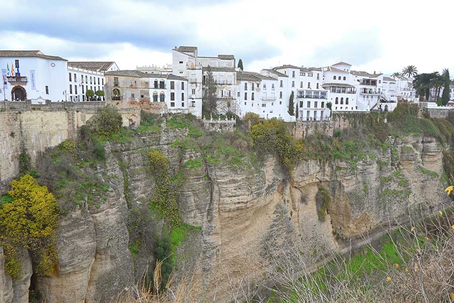 wide-panoramic-view-of-historic-white-washed-buildings-constructed-directly-on-the-edge-of-a-massive-sheer-rock-cliff