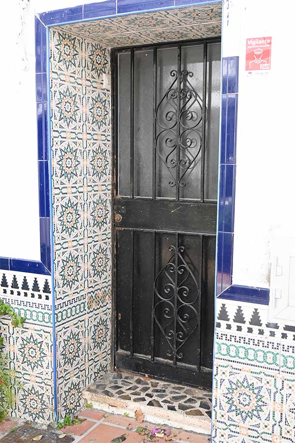 Black-metal-doorway-framed-by-vibrant-geometric-tessellated-tiles-and-a-dark-blue-border