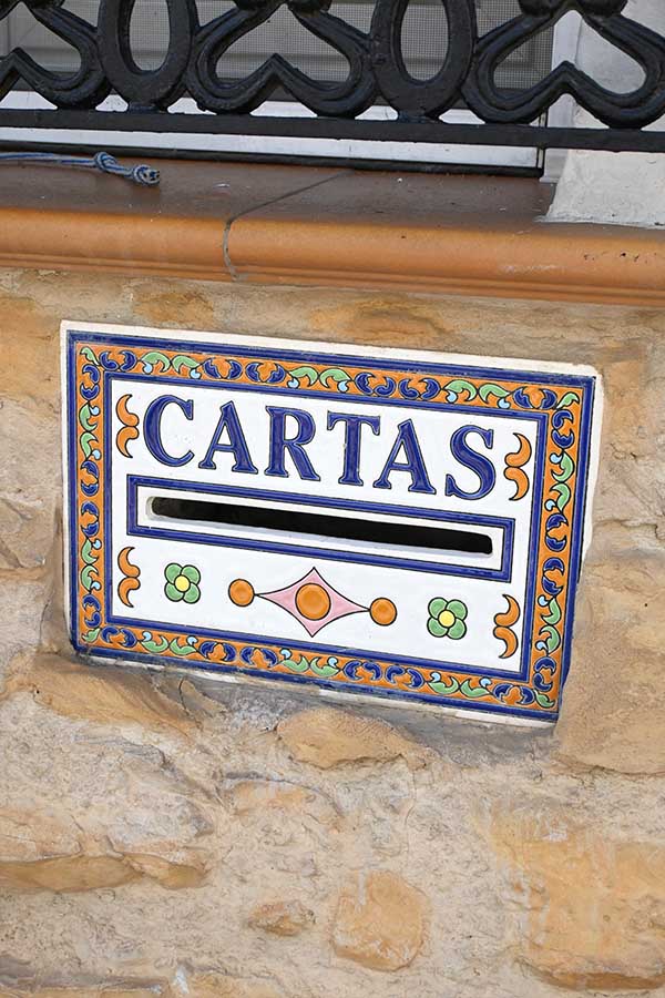Ceramic-mail-slot-tile-with-the-word-CARTAS-set-into-a-stone-wall