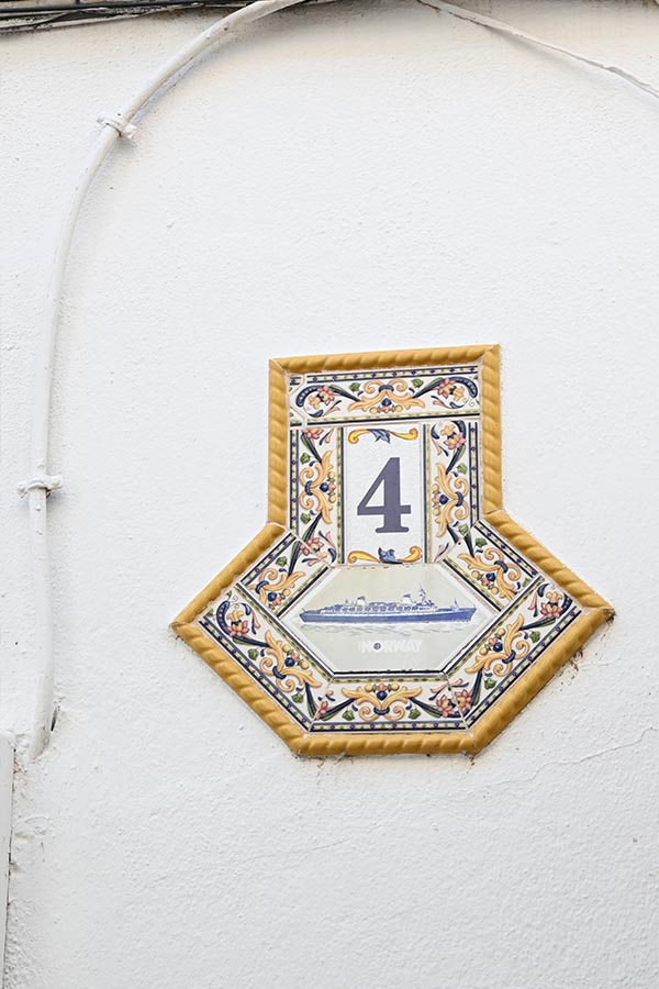 Decorative-ceramic-house-number-plaque-featuring-the-number-four-and-a-ship-on-a-white-wall