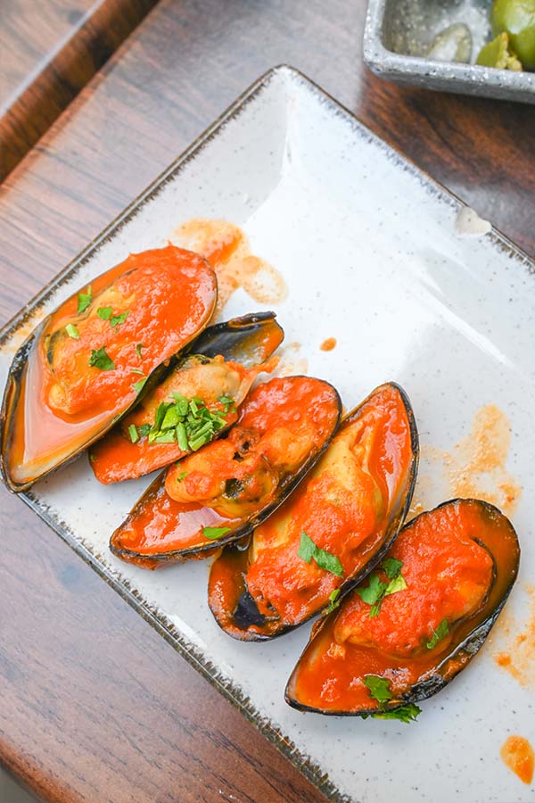 Five-mussels-served-on-the-half-shell-covered-in-vibrant-red-sauce-malaga-spain-la-esquina-granada