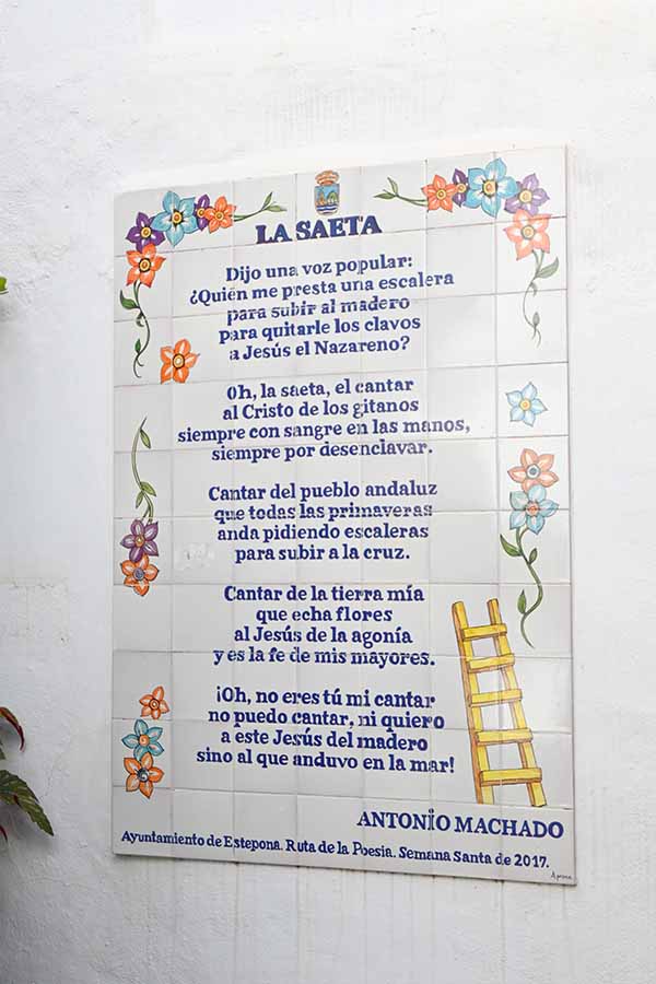 Large-tiled-plaque-on-a-white-wall-displaying-the-poem-La-Saeta-by-Antonio-Machado-with-floral-details-estepona-spain