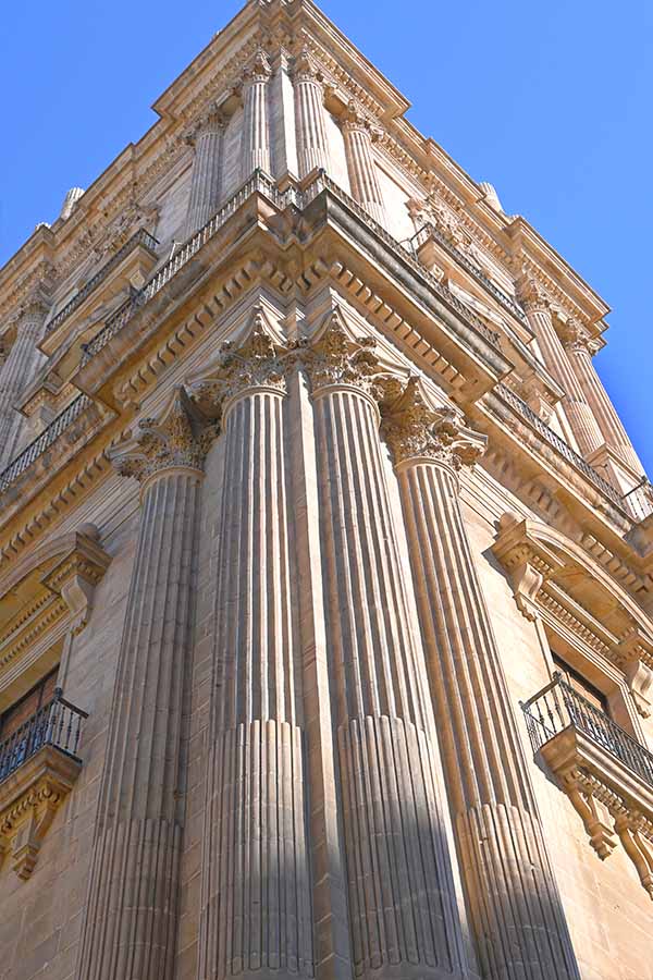 Low-angle-view-of-towering-stone-columns-and-ornate-balconies-cathedral-malaga-spain