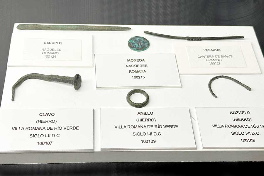 Museum-display-case-containing-six-Roman-artifacts-including-a-chisel-coin-hairpin-nail-ring