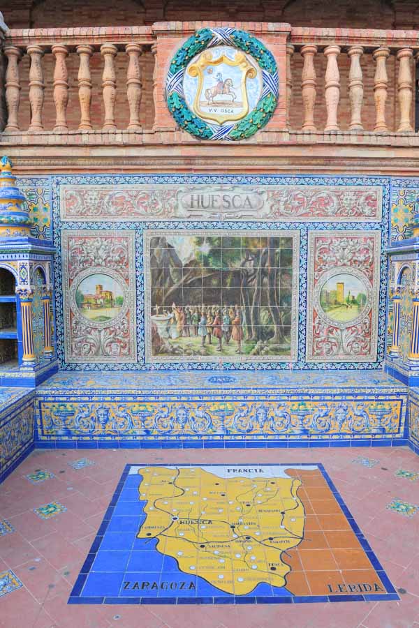 Ornate-tiled-alcove-at-Plaza-de-España-dedicated-to-Huesca-featuring-a-historical-mural-and-tiled-map