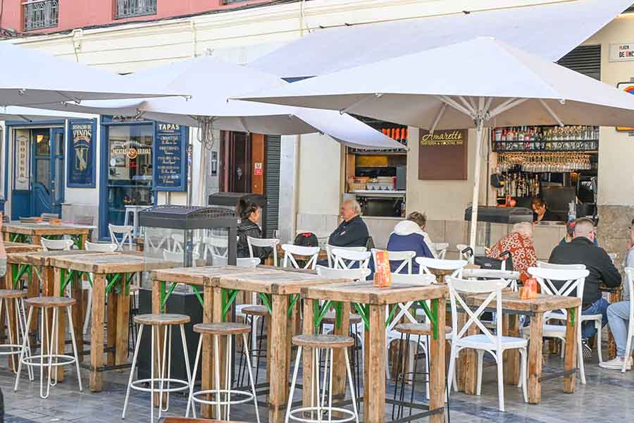 Outdoor-cafe-seating-with-wooden-tables-white-umbrellas-and-customers-relaxing-at-a-tapas-bar
