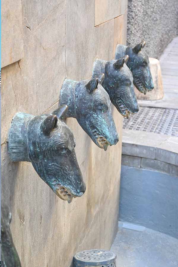 Row-of-bronze-animal-head-sculptures-mounted-on-a-stone-wall