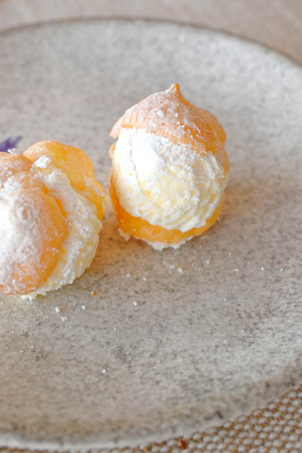 cream-filled-profiterole-pastry-powdered-sugar-plate-sweet-dessert-choux-cream-puff-delicious-spanish-bakery