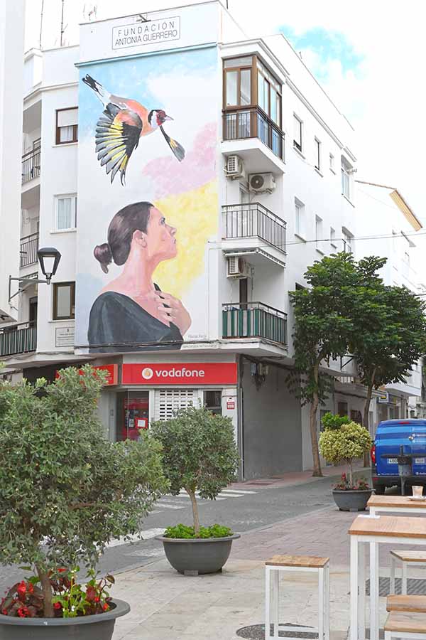 estepona-spain-apartment-building-featuring-a-large-mural-of-a-woman-and-a-bird-above-a-Vodafone-store