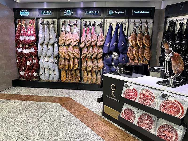 Cured-ham-legs-hanging-under-various-brand-logos