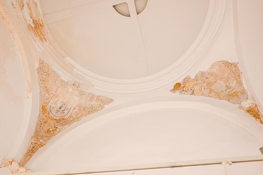 Low-angle-shot-of-a-white-domed-ceiling-featuring-faded-ornate-frescoes-and-decorative-archways