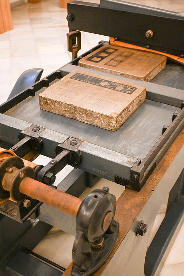 high-angle-view-of-lithographic-stones-placed-on-the-bed-of-a-vintage-printing-press