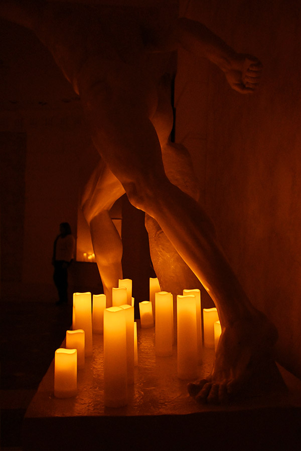 marble-statue-legs-illuminated-by-warm-battery-operated-candles-in-dim-gallery-setting