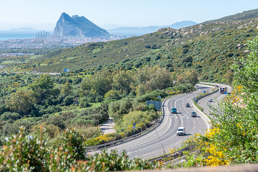 The-Rock-of-Gibraltar-is-seen-from-a-high-vantage-point-overlooking-a-winding-highway-and-lush-hills