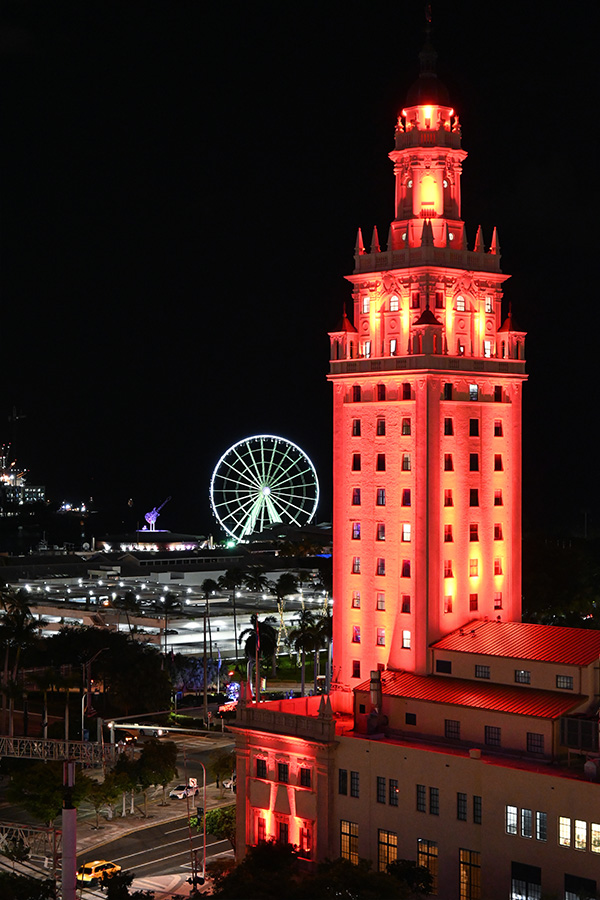 iconic-Freedom-Tower-glowing-in-vibrant-red-lighting-as-a-symbol-of-historic-Miami-architecture-with-the-observation-wheel