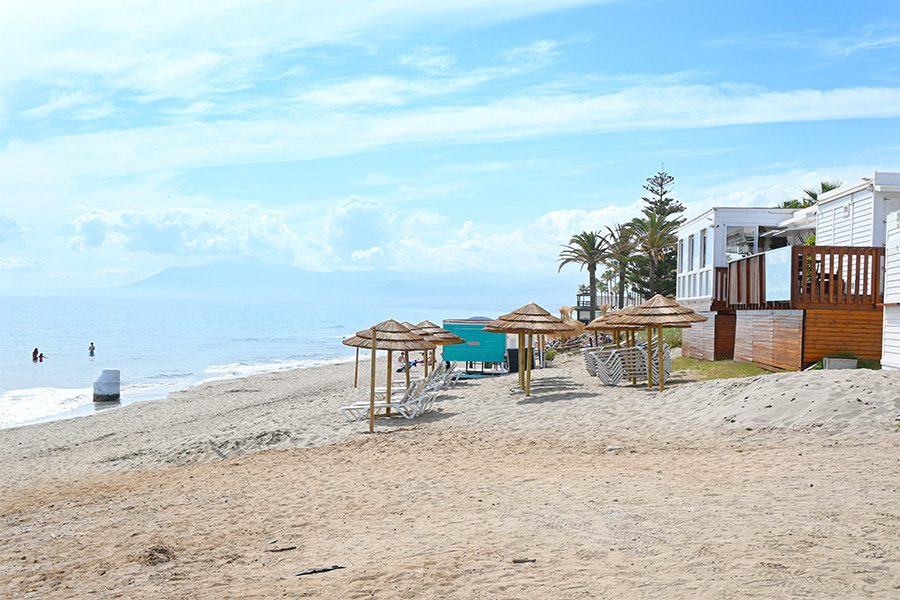 beach-umbrellas-and-white-lounge-chairs-near-a-wooden-beach-club-structure