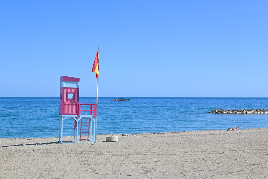pink-and-blue-lifeguard-tower-on-sandy-shore-under-clear-sky