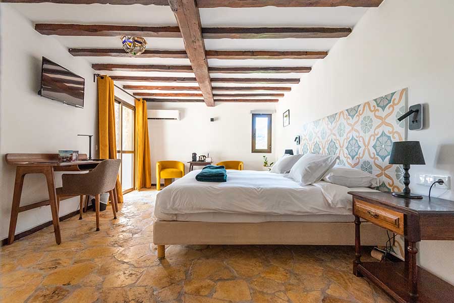 bright-hotel-room-with-patterned-headboard-and-wooden-ceiling-beams-at-hotel-castillo-de-monda-spain